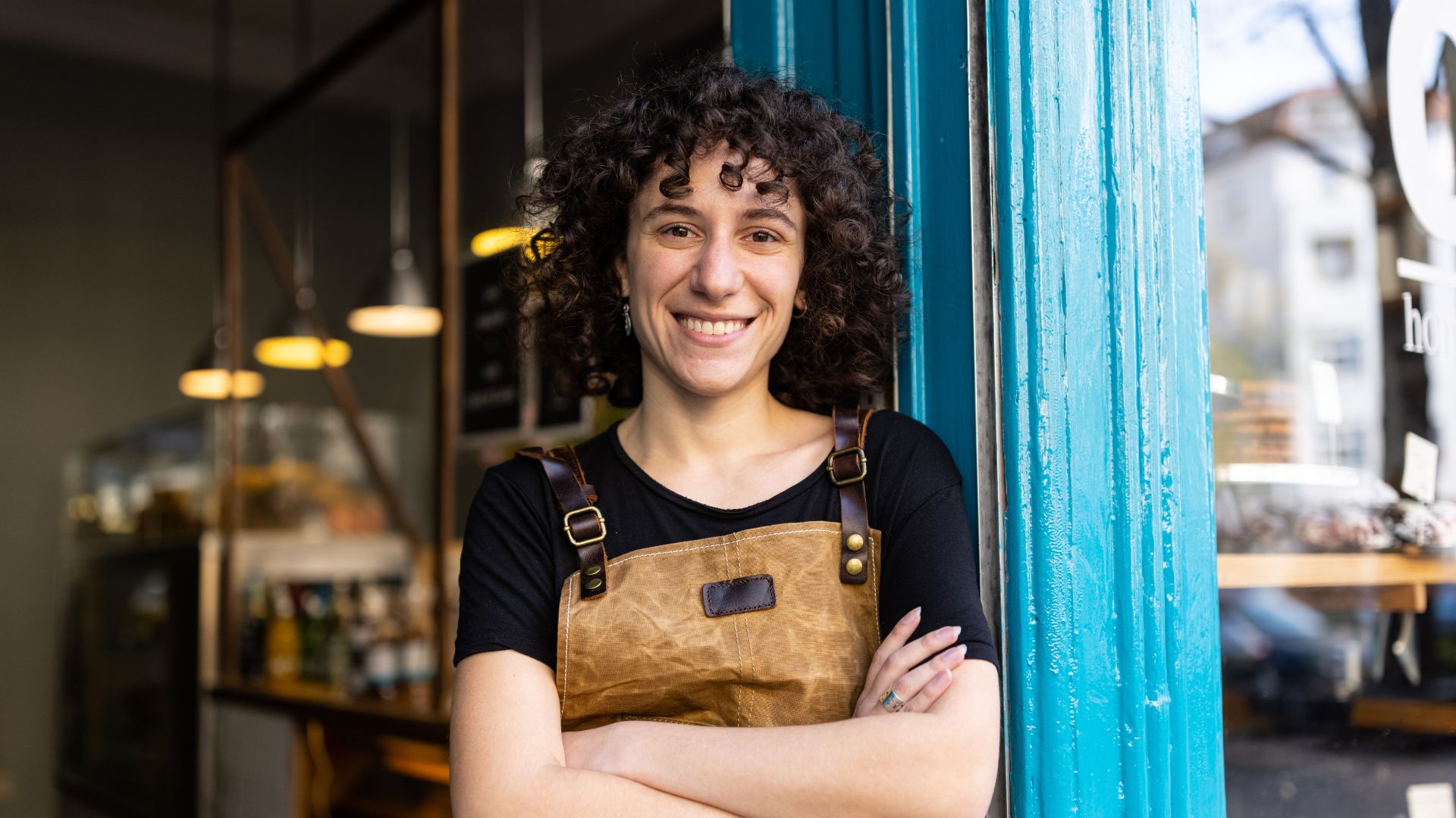 A young person smiling outside their small business.
