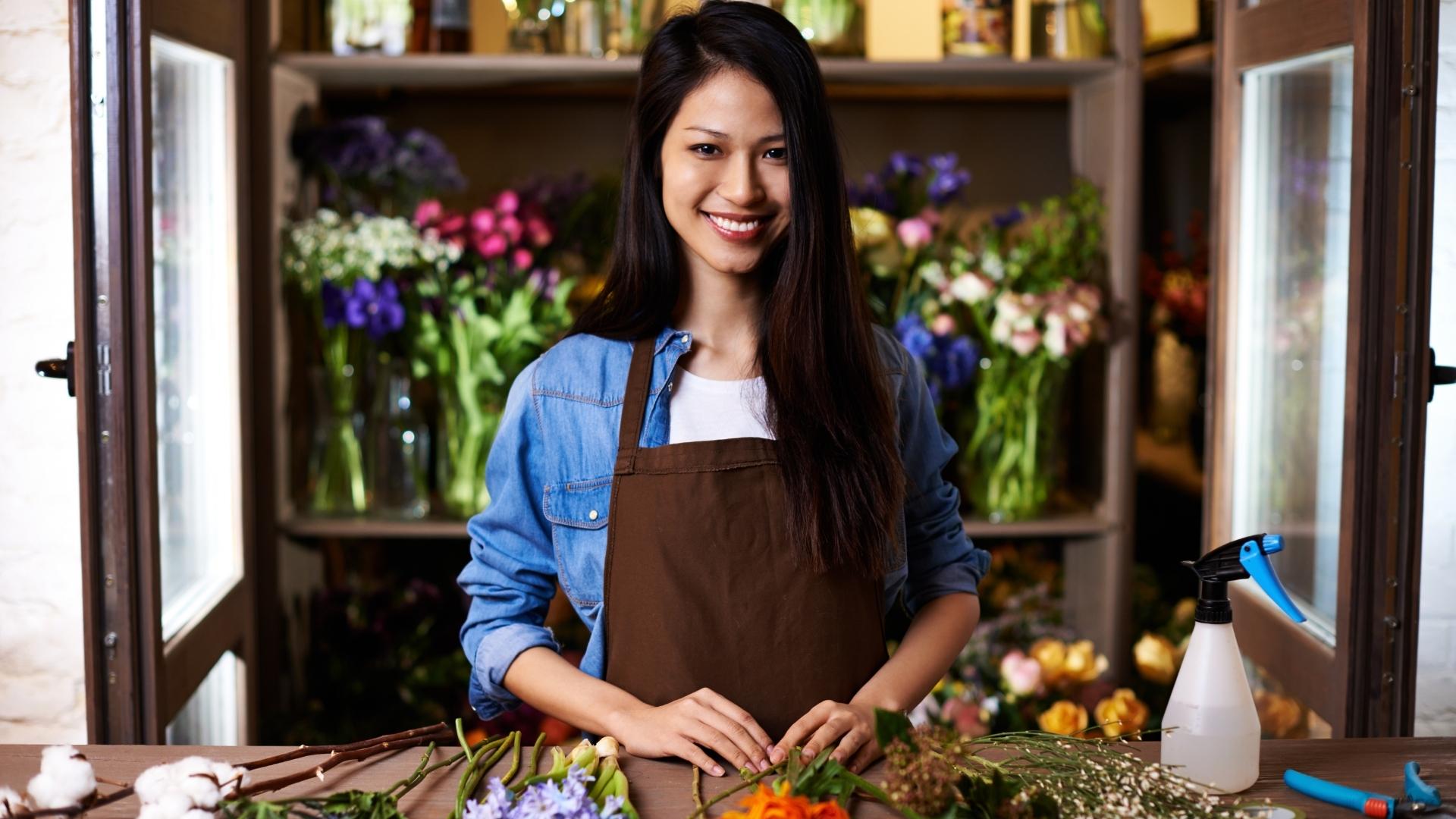 A young woman smiling in a bright, plant-filled space.
